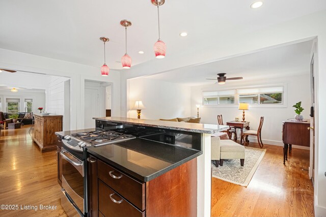 kitchen with stainless steel gas range oven, ceiling fan, and light wood-type flooring