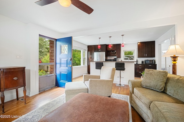 living room featuring ceiling fan, a healthy amount of sunlight, and light wood-type flooring