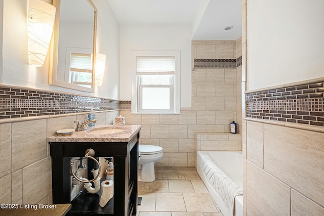 bathroom with a tub to relax in, toilet, vanity, and tile walls