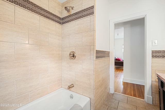 bathroom featuring tiled shower / bath combo, vanity, and tile walls