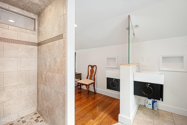 bathroom with hardwood / wood-style flooring, vanity, and tiled shower