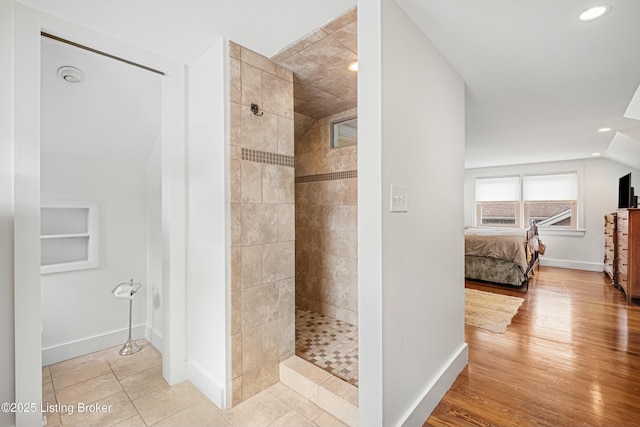 bathroom with a tile shower, wood-type flooring, and lofted ceiling