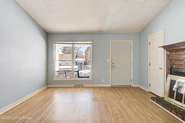 unfurnished living room with light hardwood / wood-style floors and a textured ceiling