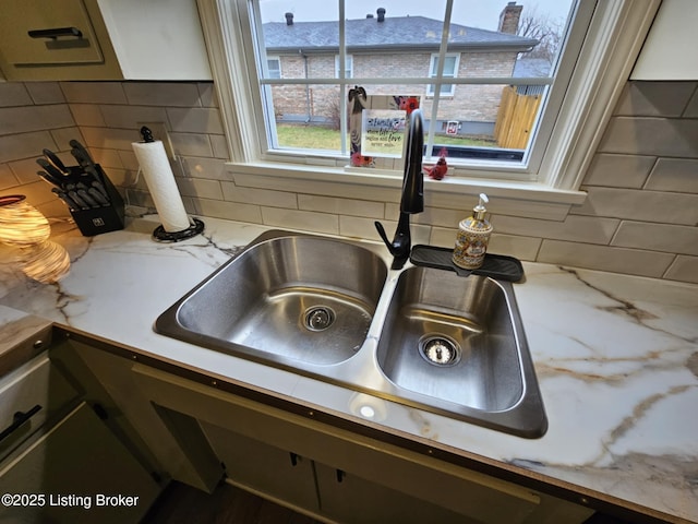 details featuring light stone countertops, sink, and backsplash