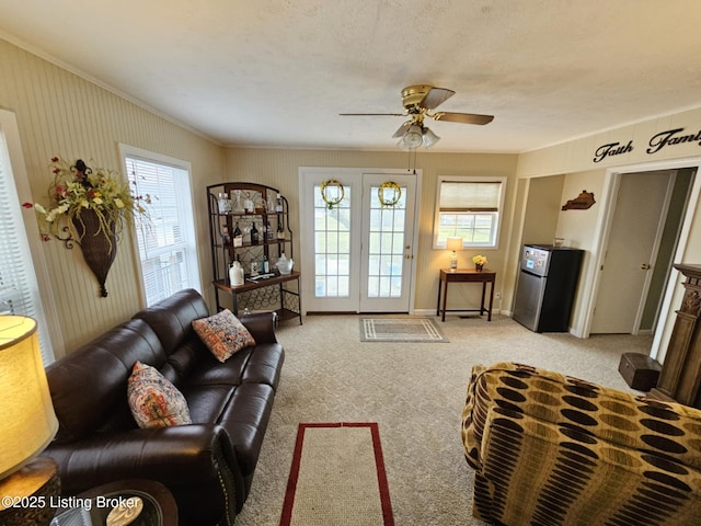 carpeted living room with crown molding, plenty of natural light, and ceiling fan