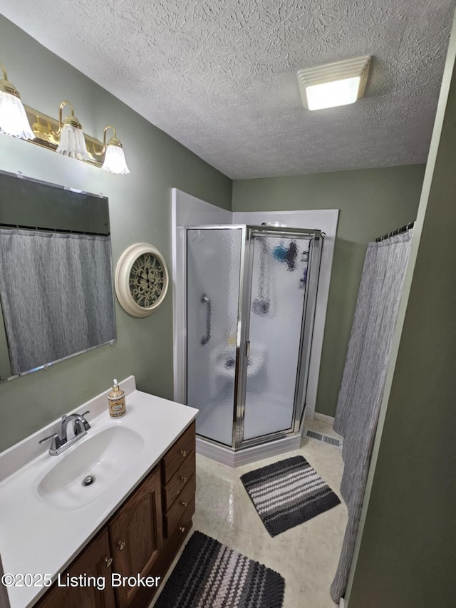 bathroom featuring vanity, a shower, and a textured ceiling