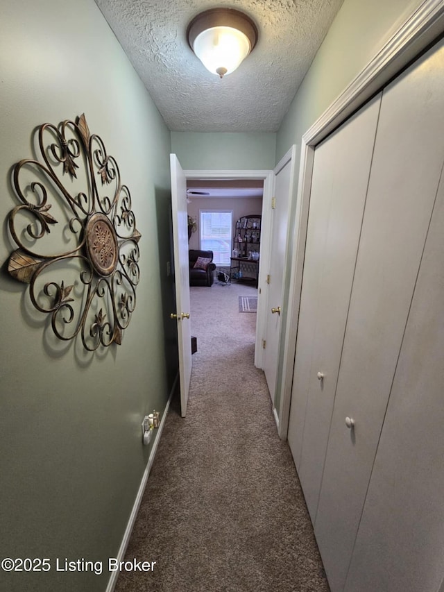 corridor featuring light colored carpet and a textured ceiling