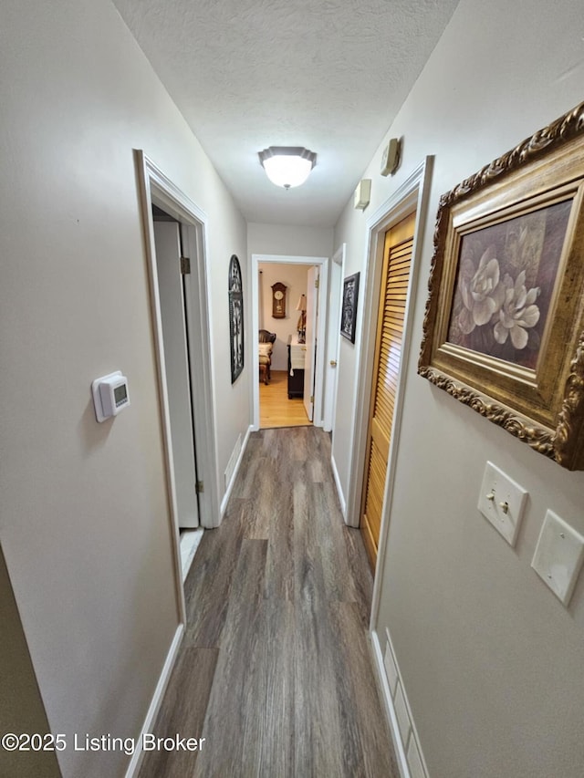 hallway with dark wood-type flooring and a textured ceiling