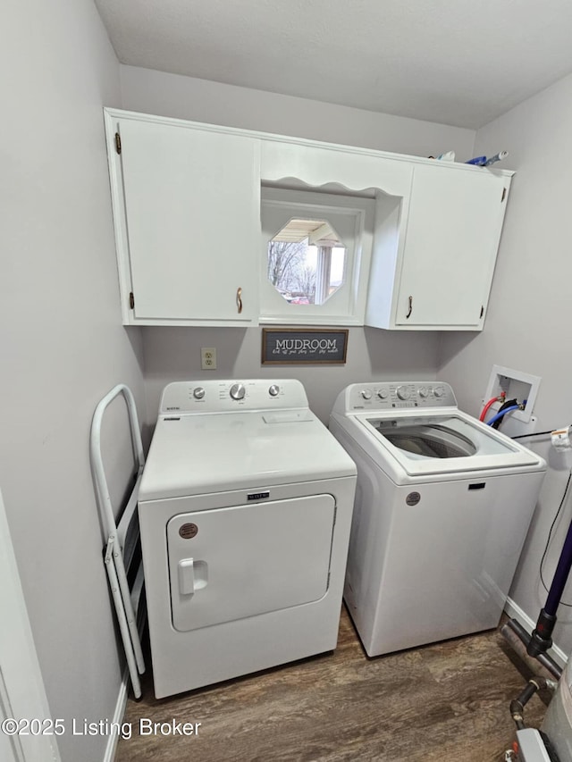 clothes washing area with cabinets, dark hardwood / wood-style floors, and washer and clothes dryer