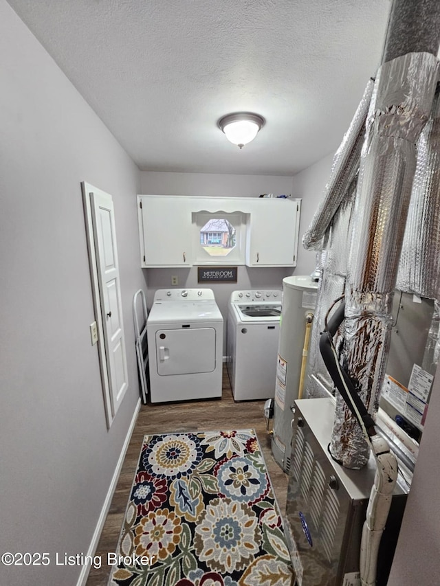 washroom with dark wood-type flooring, cabinets, washing machine and dryer, and gas water heater