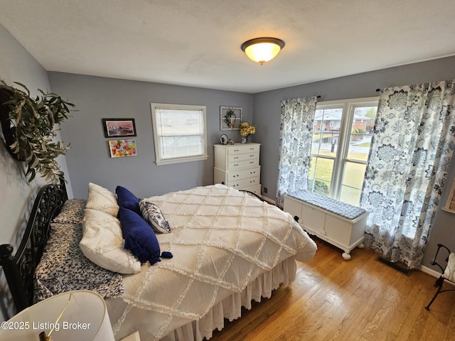 bedroom with multiple windows and light wood-type flooring