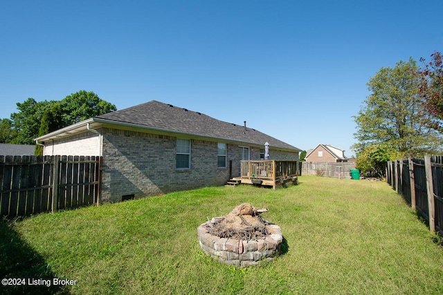 back of house with a yard, a deck, and an outdoor fire pit