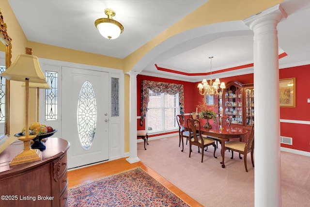 foyer with visible vents, an inviting chandelier, arched walkways, a raised ceiling, and ornate columns