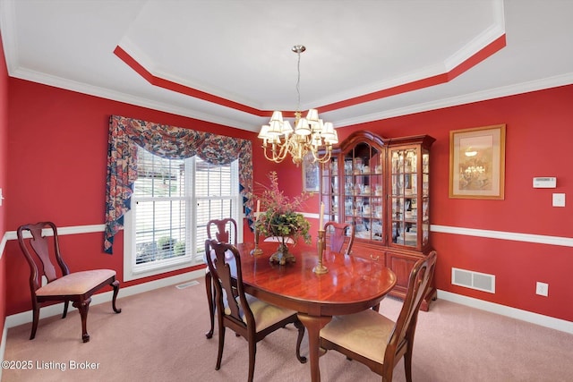 carpeted dining area with a raised ceiling, visible vents, and a chandelier