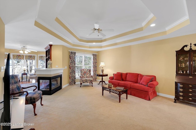 living area with carpet flooring, a tray ceiling, and ceiling fan