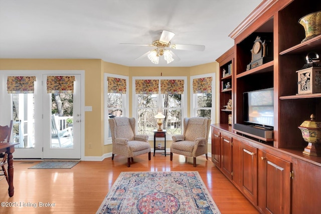 sitting room with baseboards, light wood-type flooring, and a ceiling fan