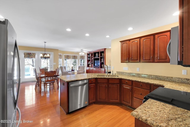 kitchen with a peninsula, recessed lighting, a sink, appliances with stainless steel finishes, and light wood-type flooring