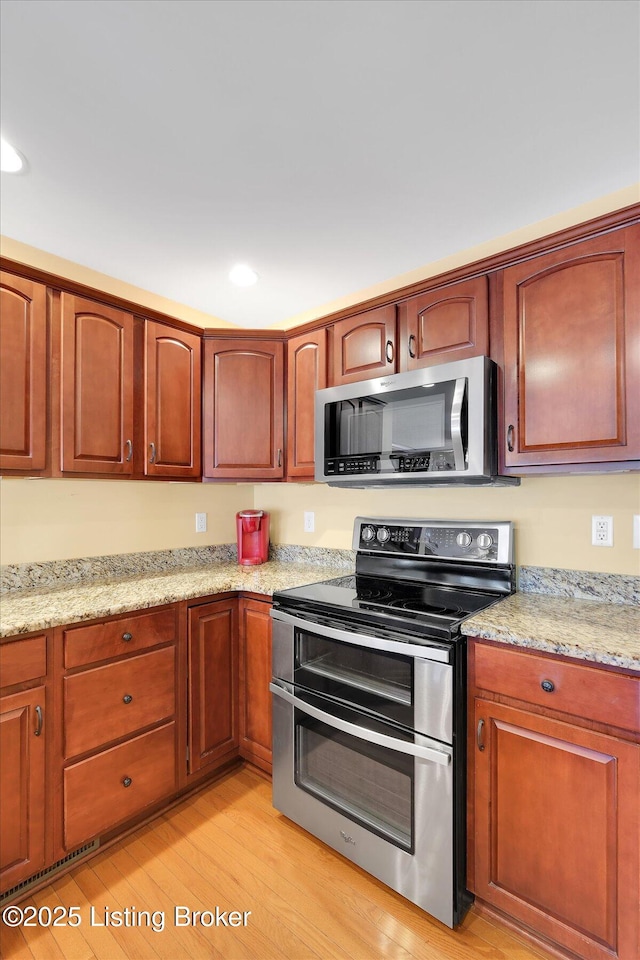 kitchen with light stone counters, recessed lighting, light wood-style flooring, and stainless steel appliances