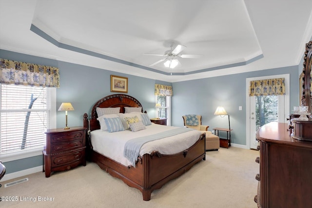 bedroom featuring a tray ceiling, multiple windows, and visible vents