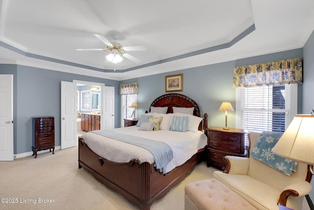 bedroom with light colored carpet, ensuite bath, crown molding, and a tray ceiling