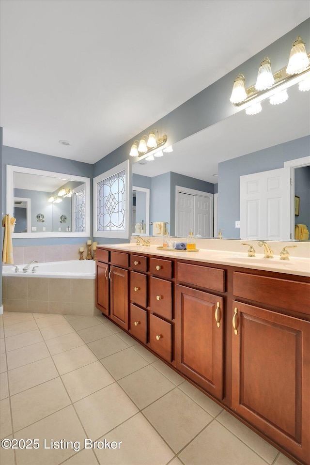 bathroom with tile patterned flooring, a garden tub, double vanity, and a sink