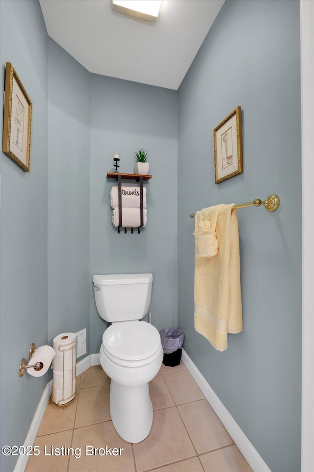 half bathroom with tile patterned floors, toilet, and baseboards