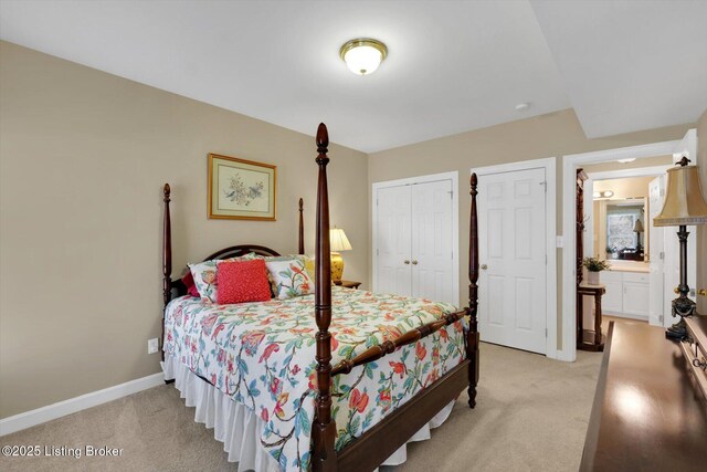 bedroom with light colored carpet, ensuite bath, and baseboards