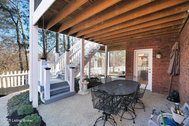 view of patio / terrace featuring outdoor dining space, stairs, and fence