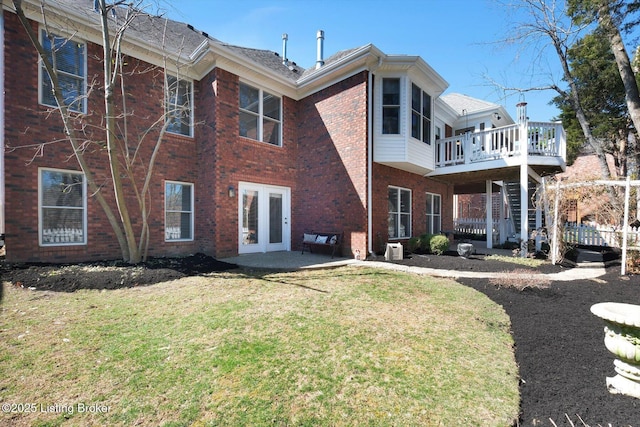 back of house with a patio, a wooden deck, stairs, a lawn, and brick siding