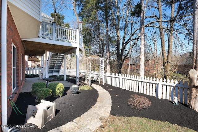 view of yard with a wooden deck, stairs, and fence