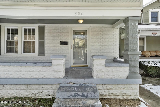 snow covered property entrance with covered porch