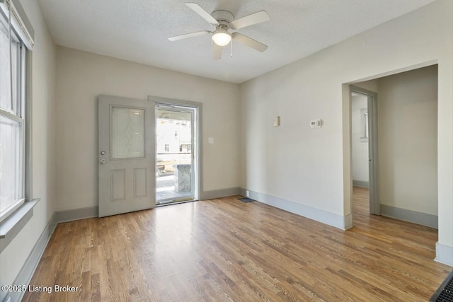 spare room with ceiling fan, light wood-type flooring, and a textured ceiling