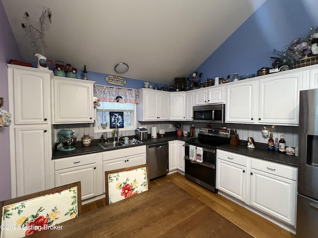 kitchen featuring lofted ceiling, sink, white cabinetry, appliances with stainless steel finishes, and dark hardwood / wood-style flooring