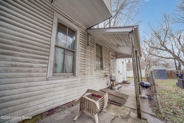 view of side of home featuring an outbuilding, a patio, a storage unit, and fence