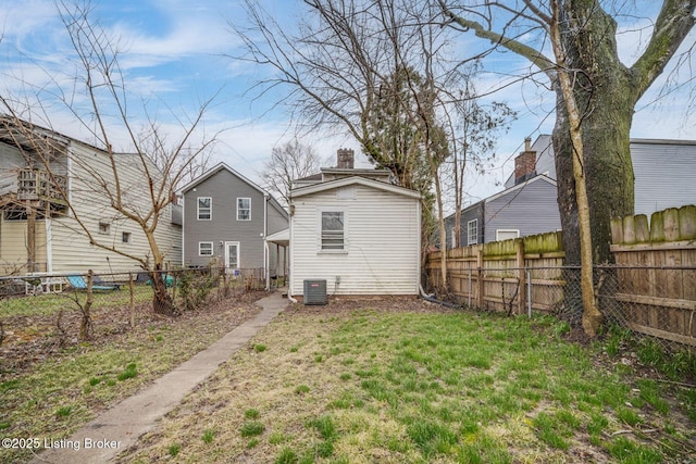 back of property with central AC unit, a chimney, and a fenced backyard