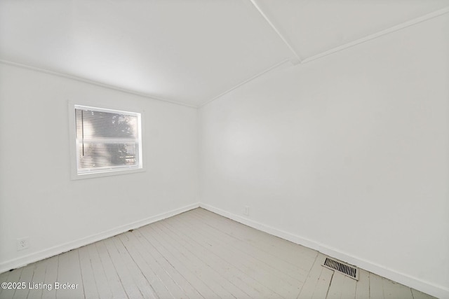 spare room with visible vents, baseboards, and wood finished floors