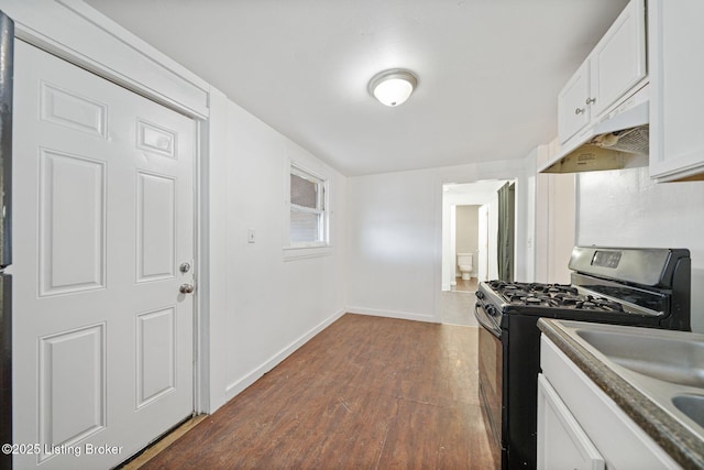 kitchen with range with gas cooktop, dark wood-type flooring, white cabinets, under cabinet range hood, and baseboards