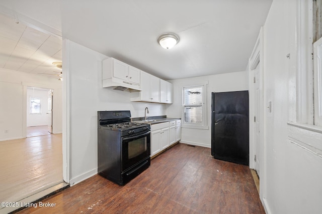kitchen with black appliances, under cabinet range hood, white cabinets, and dark wood-style flooring