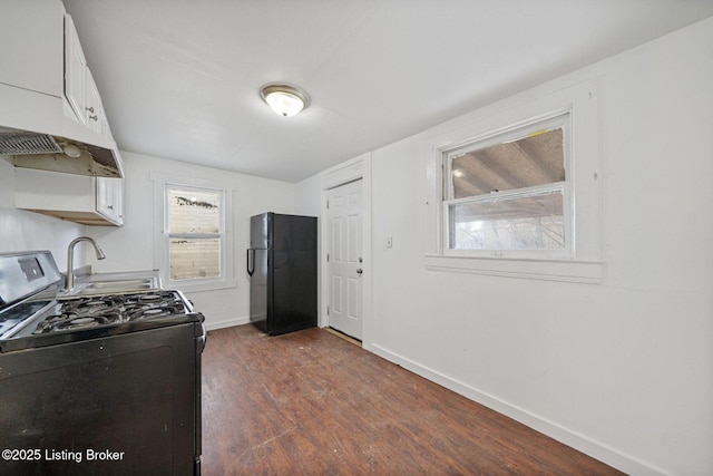 kitchen featuring a sink, white cabinetry, range with gas cooktop, freestanding refrigerator, and dark wood finished floors