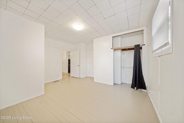 interior space featuring light wood-style flooring, baseboards, and a closet