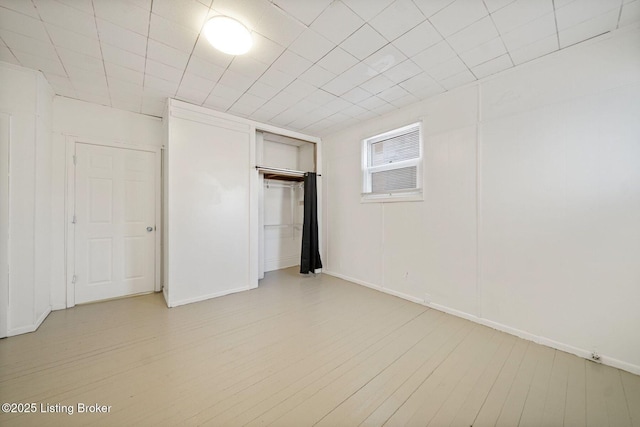 unfurnished bedroom with baseboards, a closet, and light wood-style floors