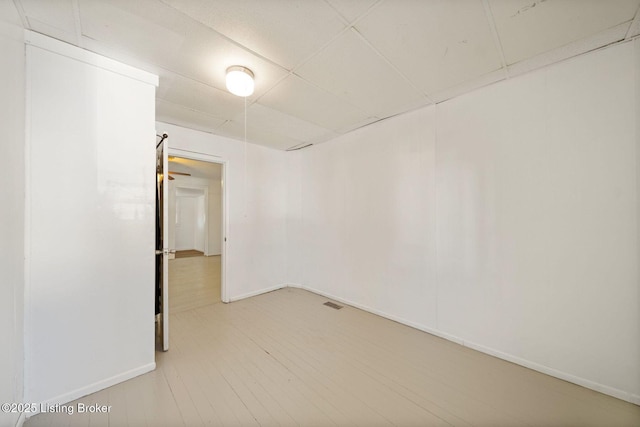 empty room featuring wood finished floors, visible vents, and baseboards