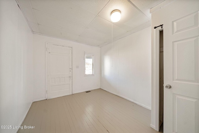 unfurnished room with a drop ceiling, wood finished floors, visible vents, and baseboards
