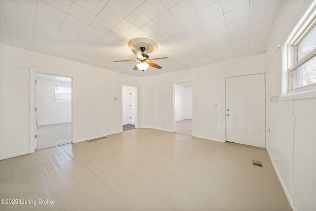 unfurnished room featuring light wood-type flooring, ceiling fan, and visible vents