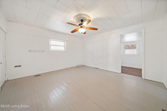 unfurnished room with visible vents, a ceiling fan, light wood-style flooring, and a healthy amount of sunlight