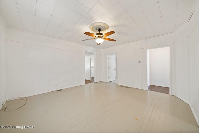 empty room featuring ceiling fan, wood finished floors, and visible vents