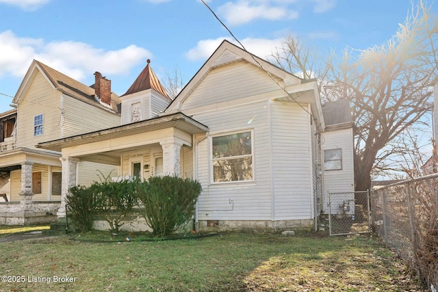 view of property exterior with covered porch, fence, and a lawn