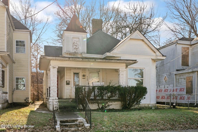 victorian home with a porch, a chimney, and a front yard