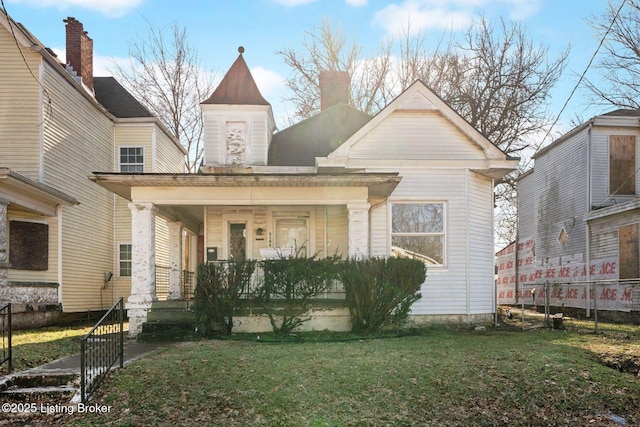 view of front of home featuring a porch, a front lawn, and a chimney