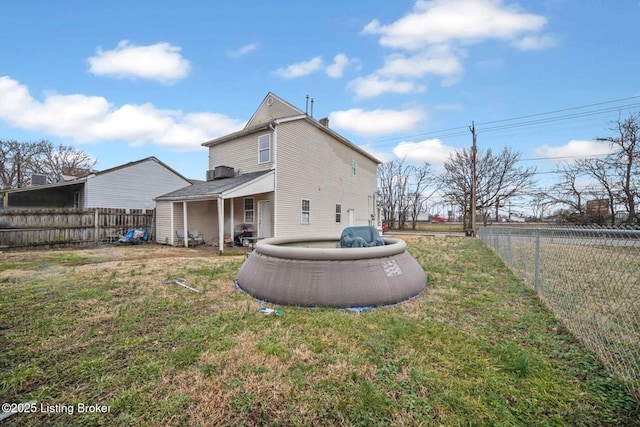 rear view of house with a lawn and a fenced backyard